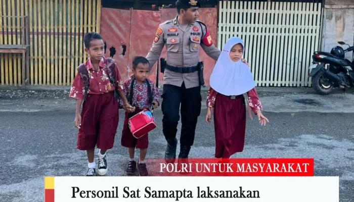 Melindungi; Seorang Anggota Samapta Polres Sula Tuntun Siswa Menyebrang